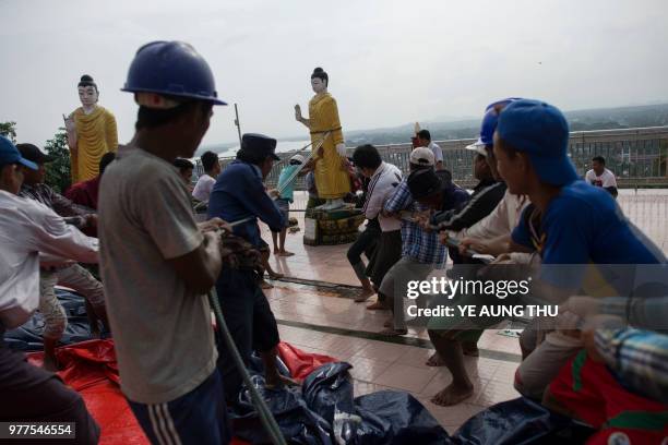 Workers save a Buddha statue after a landslide damaged the hilltop Kyeik Than Lan? pagoda in Mawlamyine capital of Mon state on June 18, 2018...