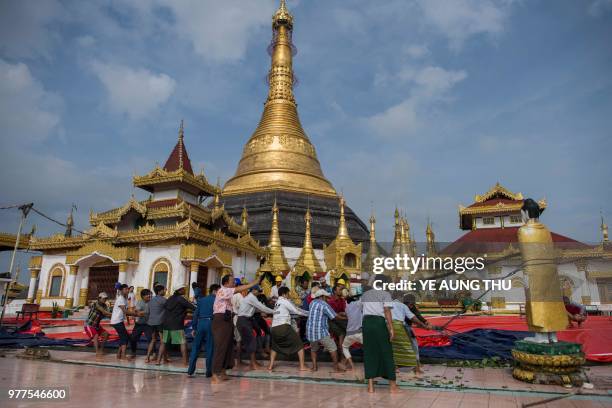 Workers save a Buddha statue after a landslide damaged the hilltop Kyeik Than Lan? pagoda in Mawlamyine capital of Mon state on June 18, 2018...