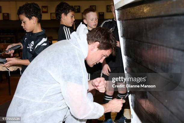 Matt Todd of the All Blacks helps paint the Pirates Rugby Club's newly built pirate ship stage during an New Zealand All Blacks community activity on...