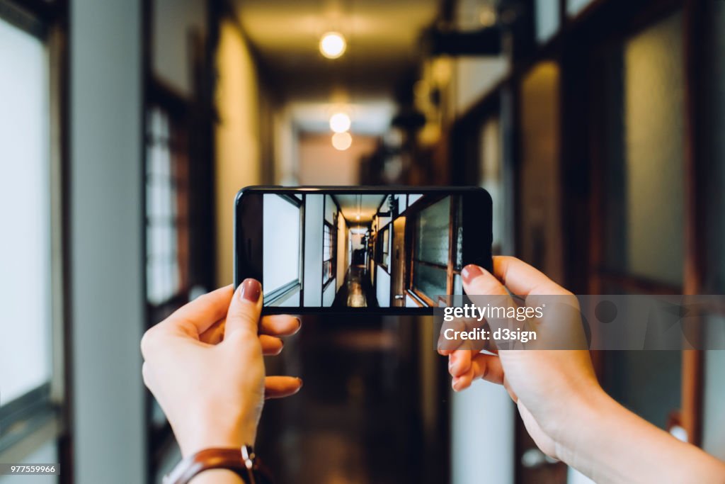 Close up of woman's hand photographing with smartphone the architecture of traditional Japanese house
