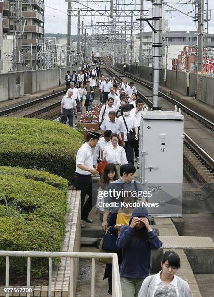 Rail passengers were forced to alight and walk along the track toward Hankyu Ikeda station in Ikeda, Osaka Prefecture, on June 18 after a powerful...