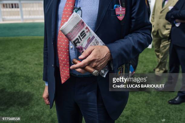 Man smokes a cigar during the 169th Prix de Diane horse racing on June 17, 2018 in Chantilly, northern Paris.