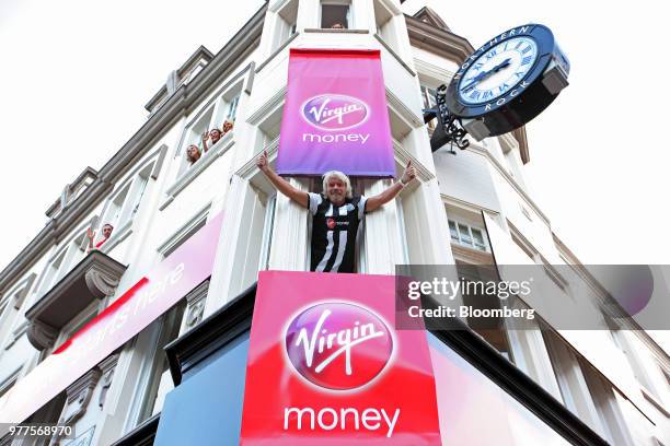 Richard Branson, the founder of Virgin Group Ltd., center, gestures from the window of Virgin Money's first high street bank while dressed in a...