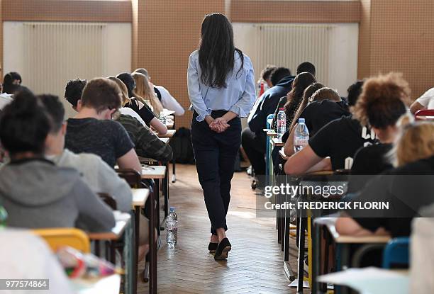 Teacher walks through a classroom as high school students work on a 4 hours philosophy dissertation, that kicks off the French general baccalaureat...