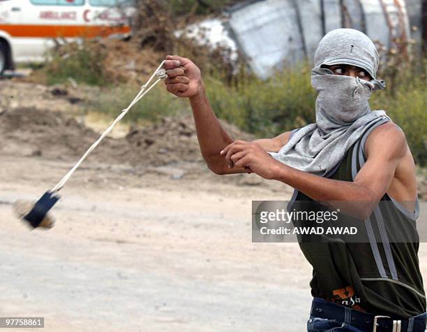 Palestinian youth uses a slingshot to hurl stones at Israeli troops in the northern Gaza Strip town of Beit Hanun 21 May 2003. The Israeli army...