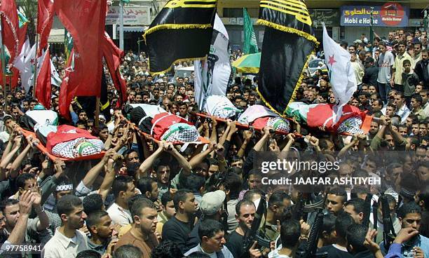 Palestinian mourners carry 03 May 2004 the bodies of four militants of Al-Aqsa Martyrs Brigades killed yesterday in an Israeli air raid, during their...