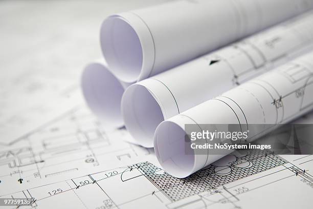 blue prints on a table with rolled blueprints - architecture blueprint stock pictures, royalty-free photos & images