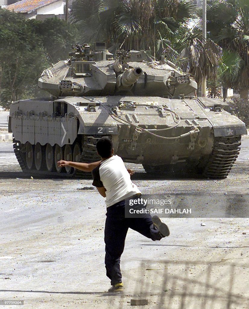 Palestinian boy throws stones at an Isra