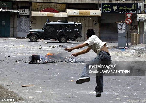 Palesinian youth hurls a rock at an Israeli police patrol in the Casbah or ancient neighborhood of the West Bank town of Nablus 24 June 2004. Three...