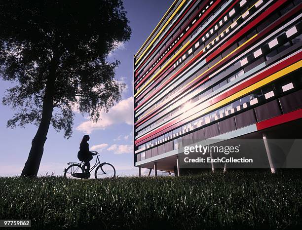 woman on bicycle arriving at colorful building. - utrecht stock-fotos und bilder