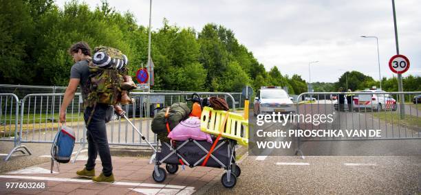 Man carries a trolley with bags past police cars near the site of the Pinkpop festival in Landgraaf, on June 18 2018, after a van slammed into...