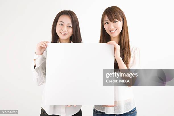 two young women holding message board - ボード　持つ　女性 ストックフォトと画像