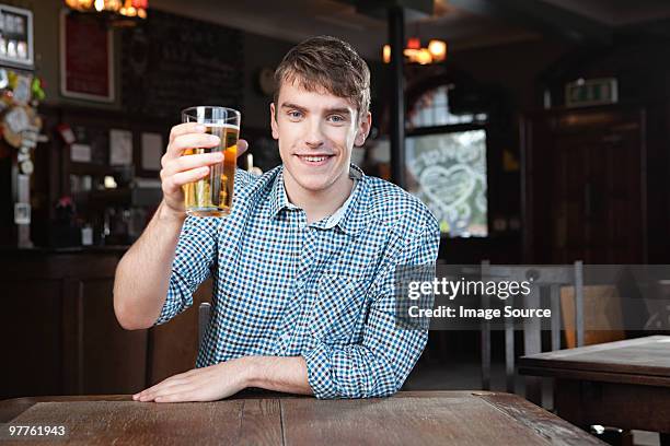 young man in bar - man sipping beer smiling photos et images de collection