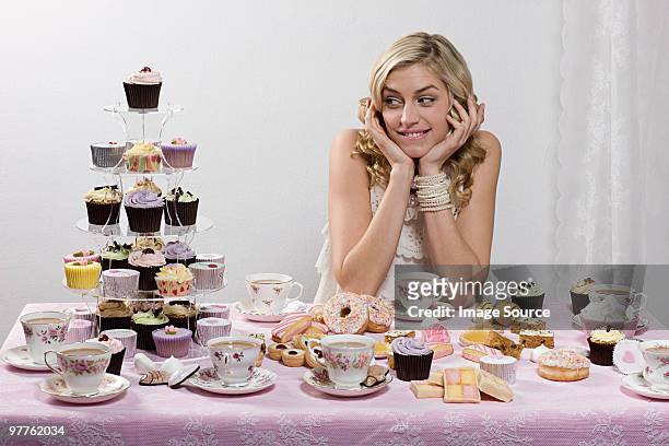 woman with table of tea and cakes - cupcake teacup stockfoto's en -beelden