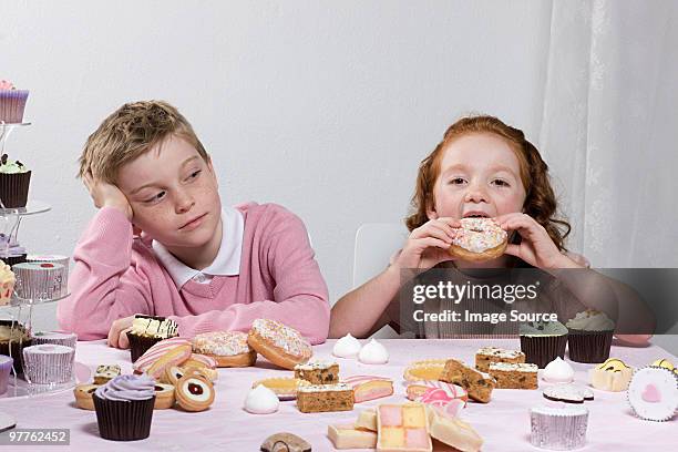 boy looking at chica comiendo buñuelo en forma de rosca - exceso fotografías e imágenes de stock
