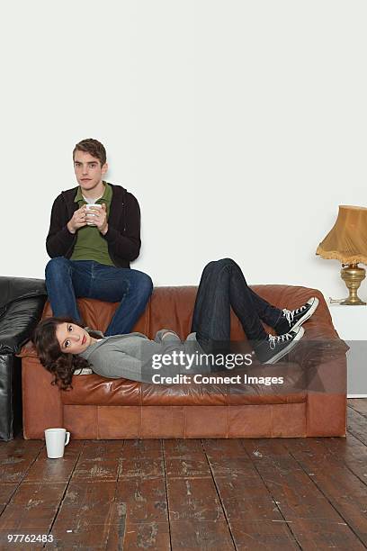 young couple on leather sofa - lewisham stock pictures, royalty-free photos & images