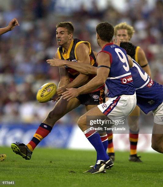 Andrew Crowell for Adelaide handballs under pressure from Paul Hudson and Patrick Wiggins for the Bulldogs in the match between the Adelaide Crows...