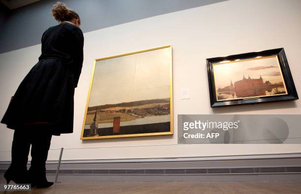 Gallery employee looks at paintings entitled 'Roof Ridge of Frederiksborg Castle with View of Lake, Town and Forest' and 'Frederiksborg Castle in the...
