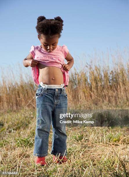 young girl looking at her belly button - belly button ストックフォトと画像