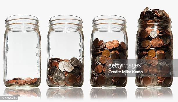 jars of coins - frugalidad fotografías e imágenes de stock