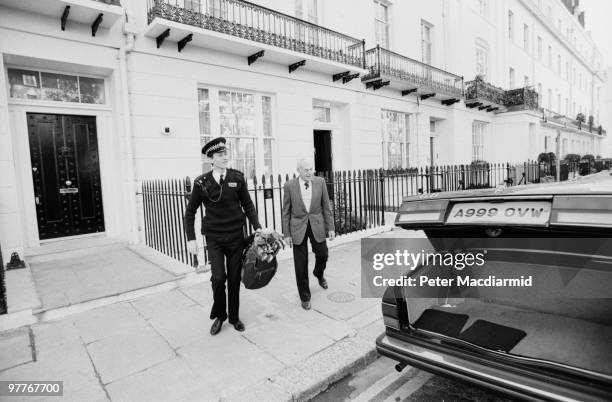 Police officer loads a golf bag belonging to Denis Thatcher , into a Rolls Royce parked outside the Thatcher's residence in Chester Square, London,...