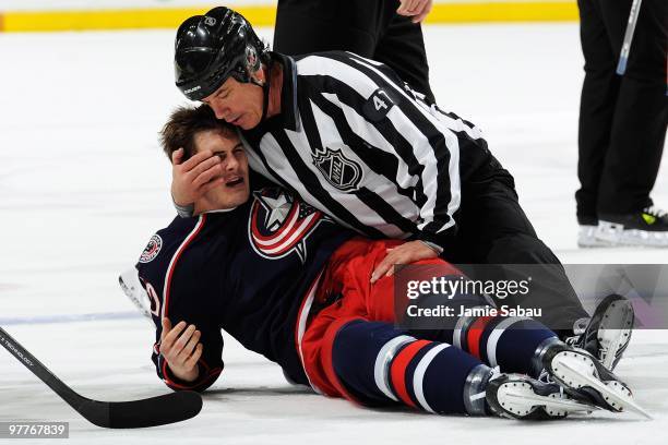 Jared Boll of the Columbus Blue Jackets is checked out by linesman Dan Schachte after being driven to the ice by Theo Peckham of the Edmonton Oilers...