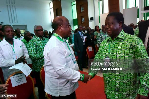 Ivory Coast's Ex-President and President of the Ivory Coast Democratic party Henri Konan Bedie shakes hands with former Ivory Coast Prime Minister...
