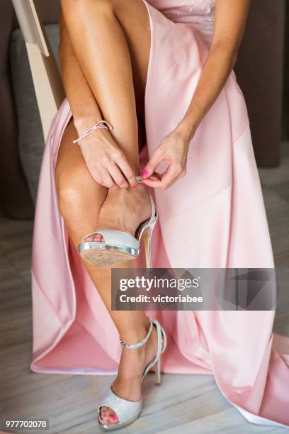 woman putting on high heel sandals - putting on high heels stock pictures, royalty-free photos & images