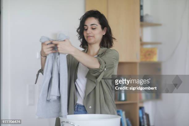 woman standing in the utility room folding clothing - gefaltet stock-fotos und bilder