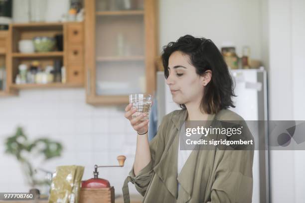 woman standing in the kitchen drinking a glass of water - standing water fotografías e imágenes de stock