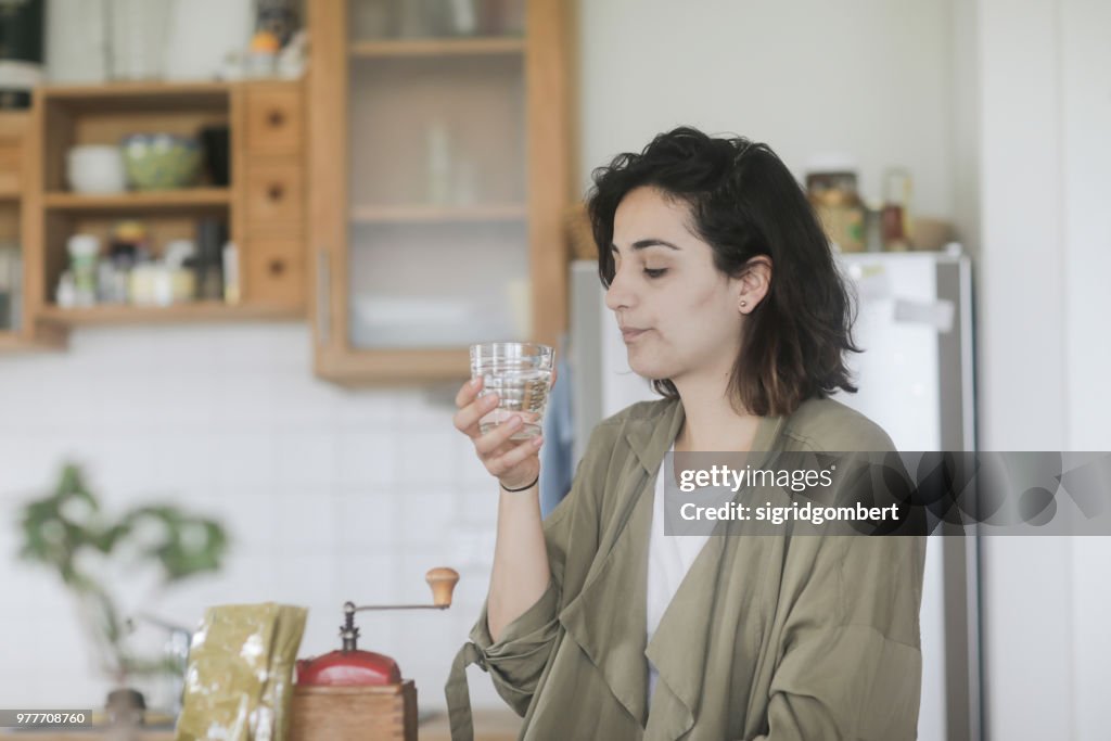 Woman standing in the kitchen drinking a glass of water