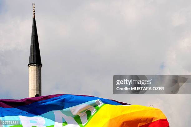 Turkish gay rights group activists wave a peace flag infront of a mosque in Istanbul on March 16, 2010 during a demonstration against Family Affairs...
