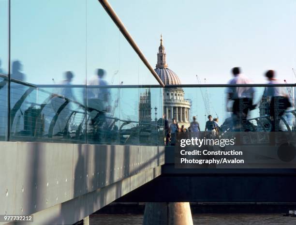 People crossing the Millennium footbridge with St Pauls Cathedral in background, London, United Kingdom, Bridge designed by Norman Foster and...