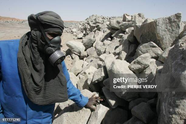 Un employé de la mine d'uranium à ciel ouvert de Arlit, dans le désert de l'Aïr , inspecte de la roche contenant de l'uranium, le 23 février 2005....