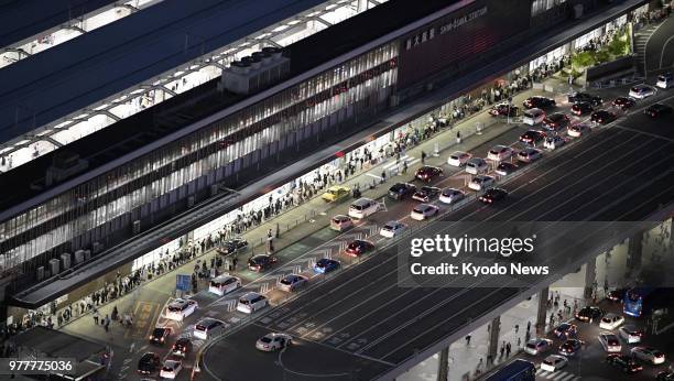 Photo taken from a Kyodo News helicopter over JR Shin-Osaka Station on June 18 shows people lining up for taxis as public transportation remains...