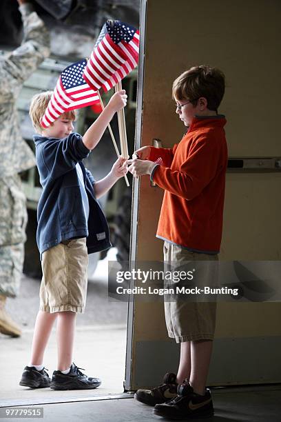 Brothers Colby Blackwell and Chase Blackwell hand out american flags as family and friends prepare to welcome troops from the 82nd Combat Aviation...