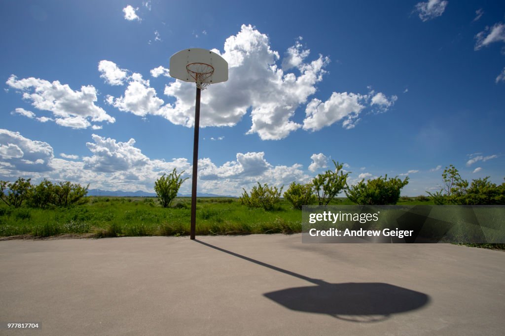 Abandoned basketball court in rural prairie filed at old school.