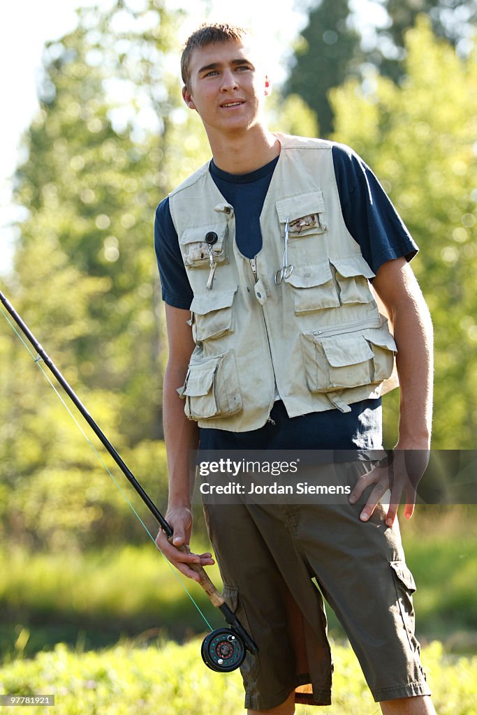 A portrait of a teenage boy fly fishing in Swan River near Bigfork, Montana.