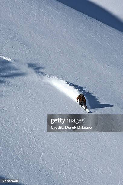 a man snowboards down a slope on teton pass, wyoming. - jackson wyoming foto e immagini stock