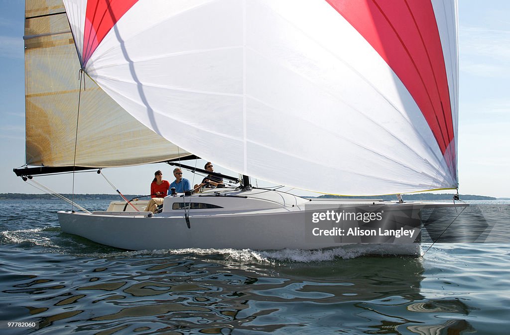 Three adults enjoying a sunny day on board a daysailer on Casco Bay, Maine.