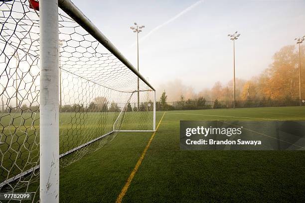 a pristine sport turf field and white post soccer goal viewed in autumn fog and morning light. - soccer goal post stock pictures, royalty-free photos & images