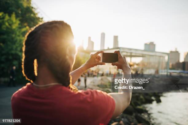 afro-karibischen kerl nehmen foto von brooklyn bridge - afro caribbean and american stock-fotos und bilder