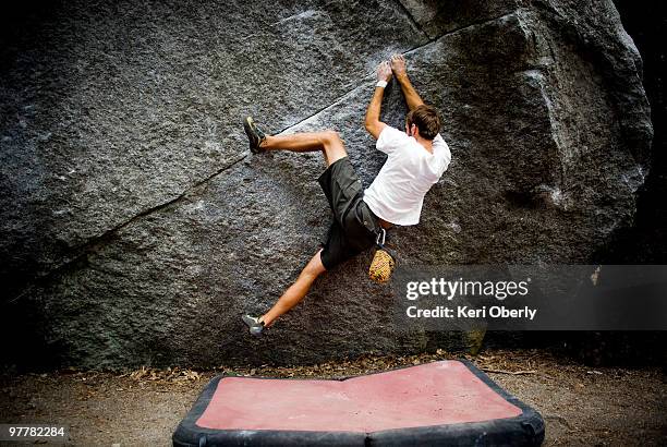 a young man's heal hooks a boulder located in yosemite valley, california. - bouldering - fotografias e filmes do acervo