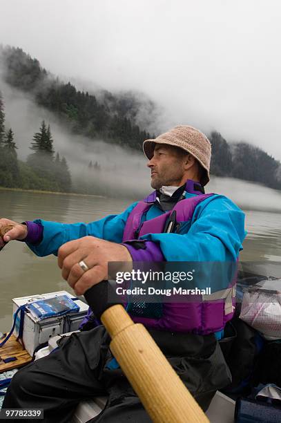 a man rows a raft into the fog on calm water in alaska. - stikine river stock pictures, royalty-free photos & images