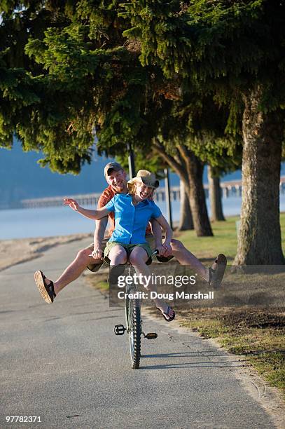 a young woman rides on the handle bars of a young man's cruiser bike in sandpoint, idaho. - tandem bicycle foto e immagini stock