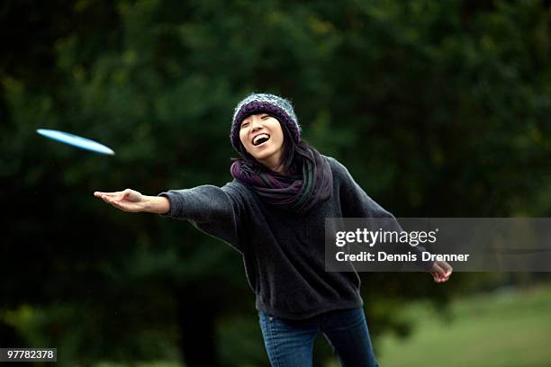a young asian-american woman throws a flying disk while playing flying disk golf in baltimore, maryl - frisbee stock pictures, royalty-free photos & images