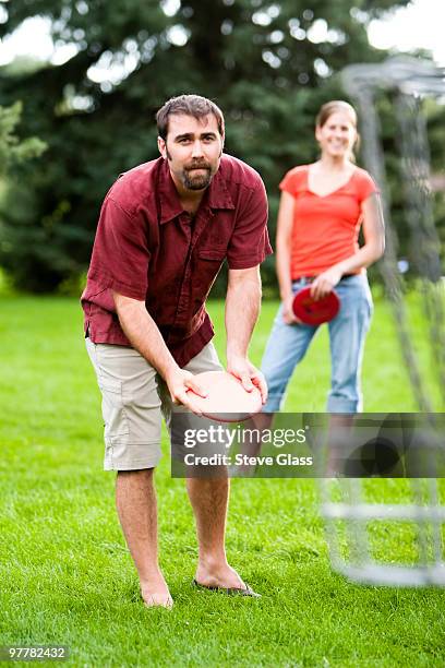 a man and woman play disk golf. - frisbee golf stock pictures, royalty-free photos & images