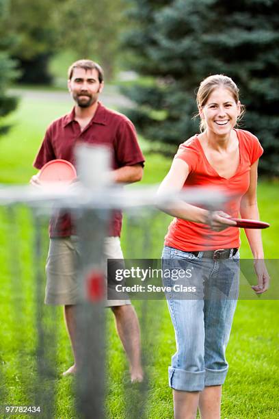 a man and woman play disk golf. - disc golf stock pictures, royalty-free photos & images