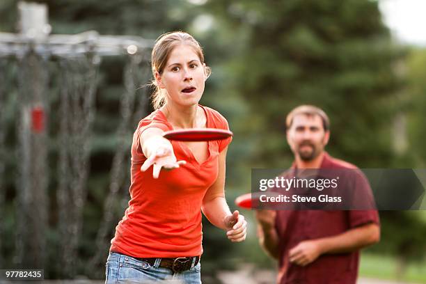 a man and woman play disk golf. - frisbee golf stock pictures, royalty-free photos & images