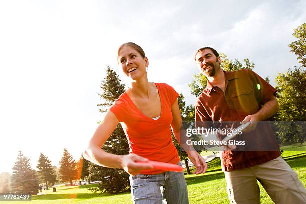 a man and woman play disk golf. - disc golf stock pictures, royalty-free photos & images